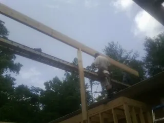 Carpenter setting a ridge beam over a new addition frame — Ice Dam Removal by Roofing Brothers in Splendora