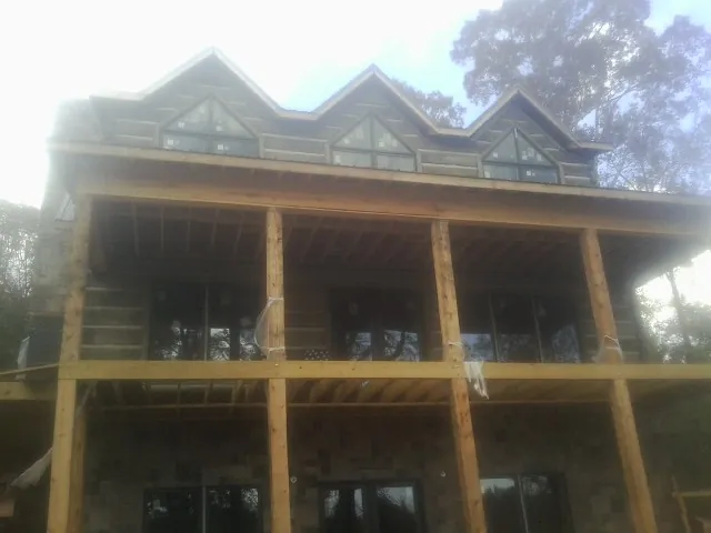 Dormers and porch framing on a large log home under construction — Roof Coating work by our crew in Splendora
