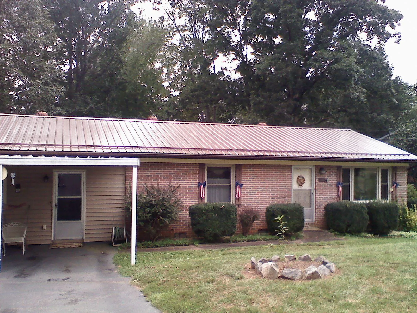 Bronze metal roof and carport on a brick ranch home — Roof Repair work by our crew in Splendora