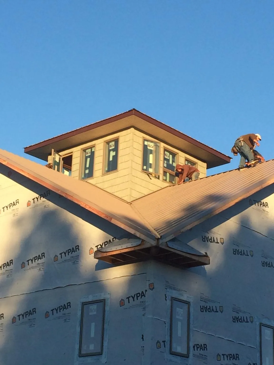 Roofers working around a rooftop cupola on a new metal roof at sunset — Roof Waterproofing in Splendora by Roofing Brothers